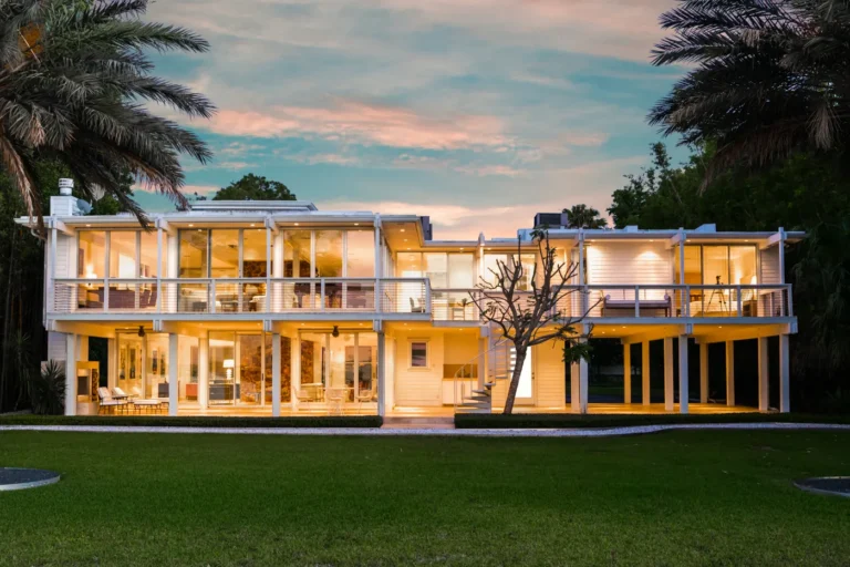 Modern glass waterfront home lit at twilight on the Texas Gulf Coast